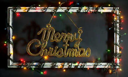 Glowing Christmas tree garland on old frame with decorations and gifts. On a blue wooden background.の写真素材