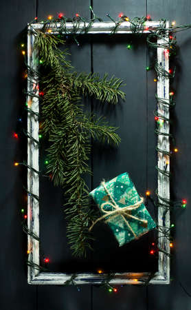 Glowing Christmas tree garland on old frame with decorations and gifts. On a blue wooden background.の写真素材