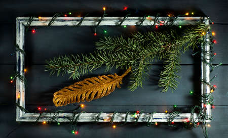 Glowing Christmas tree garland on old frame with decorations and gifts. On a blue wooden background.の写真素材