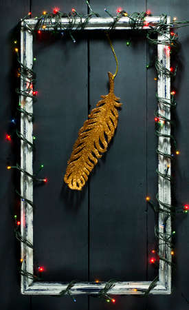 Glowing Christmas tree garland on old frame with decorations and gifts. On a blue wooden background.の写真素材
