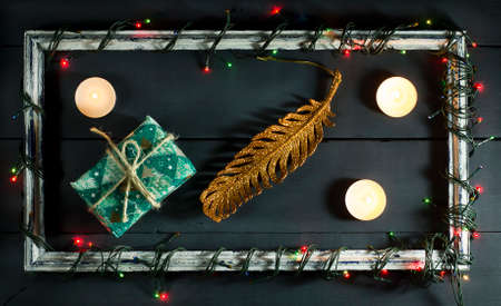 Glowing Christmas tree garland on old frame with decorations and gifts. On a blue wooden background.の写真素材