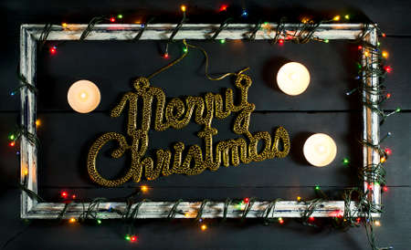 Glowing Christmas tree garland on old frame with decorations and gifts. On a blue wooden background.の写真素材