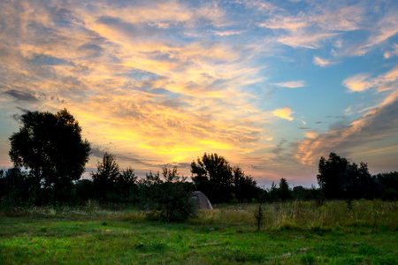 Beautiful sunrise in a field with amazing clouds. Tent. Travels. Tourismの写真素材