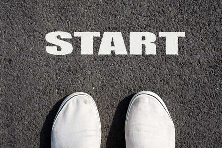 Two white sneakers on black asphalt. The inscription START. View from above. Copy space. Backgrounds.の写真素材