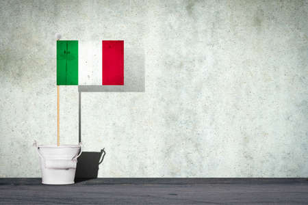 Flag of Italy, on a stick, in a small bucket, against the background of a concrete wall. Copy space. Signs and Symbols. Flags.の写真素材