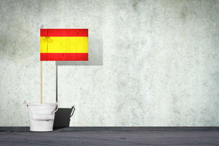 Flag of Spain, on a stick, in a small bucket, against the background of a concrete wall. Copy space. Signs and Symbols. Flags.の写真素材