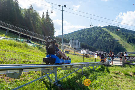 Bukovel. Ukraine. 9. August. 2020. Happy young couple on the Speed Fan slide. Entertainment. Carpathians. Summer rest Tourism Travelsのeditorial素材
