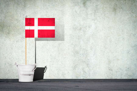 Flag of Denmark, on a stick, in a small bucket, against the background of a concrete wall. Copy space. Signs and Symbols. Flags.の写真素材