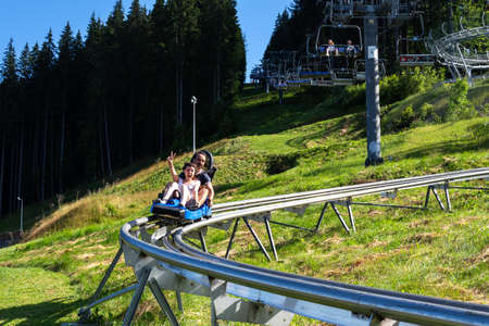 Bukovel. Ukraine. 9. August. 2020. Happy young couple on the Speed Fan slide. Entertainment. Carpathians. Summer rest Tourism Travelsのeditorial素材