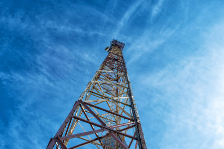 Metal tower for mobile communications, against the blue sky. Bottom view. Communication.