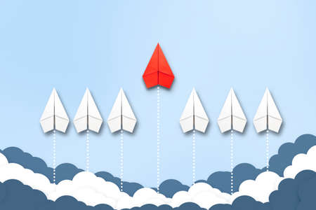 Red paper plane flying in a different direction than the white ones. Cloudy sky. Copy space. The concept of innovative solutions, creativity. Business. Lifestyle. Background.の写真素材