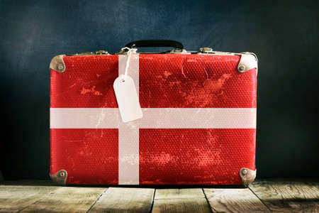 Old suitcase with flag of Denmark on wooden background. Travels.の写真素材