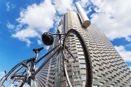 Copenhagen. Denmark. July 23, 2019. Bicycle in front of the facade of a modern metal building on a background of cloudy sky. View from below. Power station in the city of Copenhagen, attractions.のeditorial素材