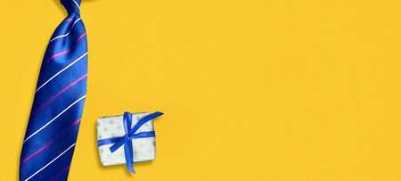 Tie and a gift on a yellow background. Copy space. Happy father's day background. Greeting card. Festive background.の写真素材