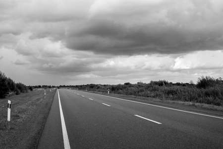 Highway going to the horizon. Beautiful thunderclouds. Black and white photo. Auto travel. Travel.