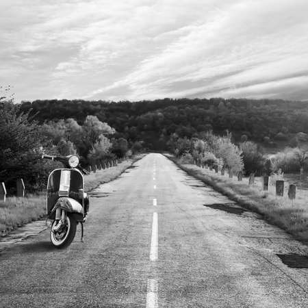 Scooter parked on the side of the track. Black and white photo. Transport. Travels. Background.
