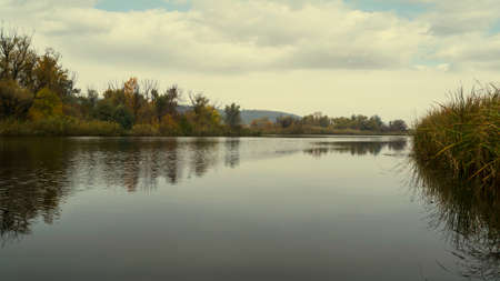A river with autumn trees and beautiful clouds. Recreation. Travels. Fishingの写真素材