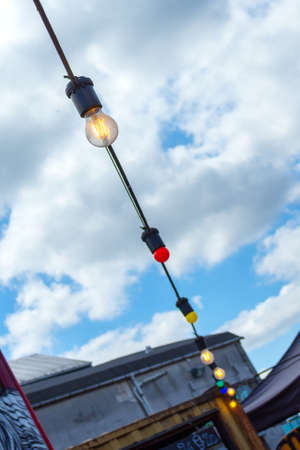 Street garland of light bulbs against the blue sky. Exterior. Close-up. Street decorations.
