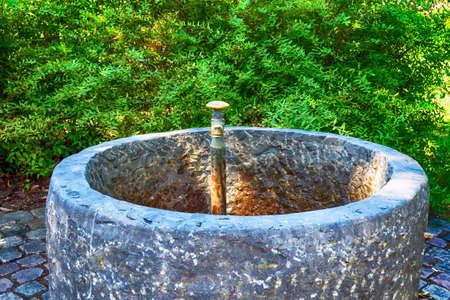 Old water tap with concrete well in the park. Detailsの写真素材