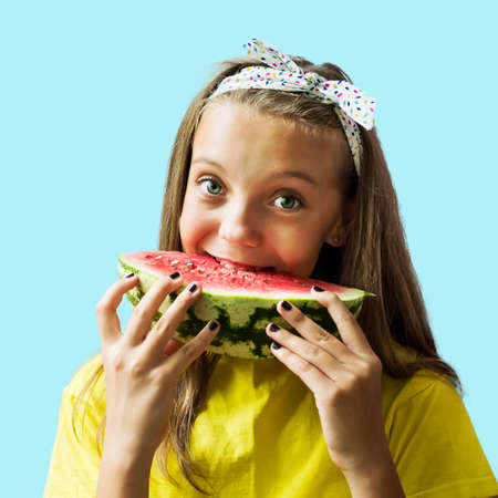 Cute, fair-haired, green-eyed girl with a watermelon. Isolated. Blue background. Healthy eating Fresh fruits and vegetables.の写真素材