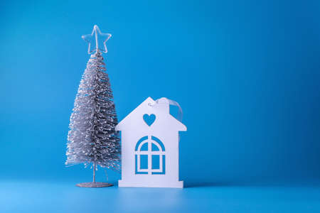 Christmas tree and white wooden house on a blue background. Copy space. Place for text. Christmas, New Year background. Festive background.の写真素材