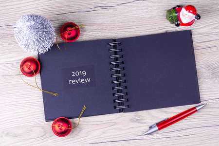 2019. Review. The concept of the analysis of the past year. Notepad with festive decor on a wooden table. Copy space. Business. Analysis.の写真素材