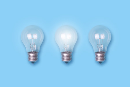 One luminous bulb and two not luminous on a blue background. The concept of new ideas. Business. Creation. Ideas.の写真素材