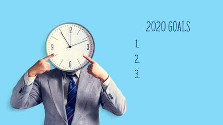 Businessman with a clock instead of ahead. The concept of goals for 2020.opium of space. Place for text. Business. Goals. Background.の写真素材