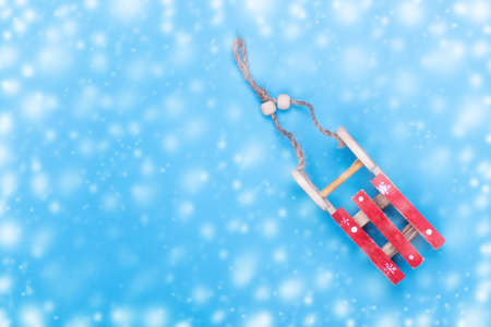 Sled on a blue background. The effect of snow. Winter holiday concept. Copy space. New year...
