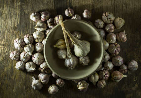 Heads of garlic in a bowl on the old wooden background. Top viewの写真素材