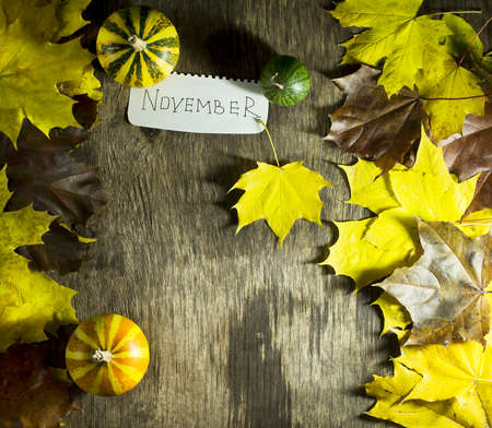 Colorful autumn leaves with pumpkins on a wooden background. Top view with copy space