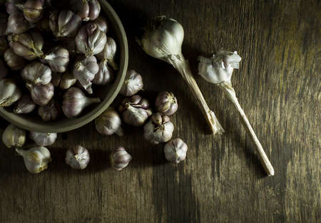 Heads of garlic in a bowl on the old wooden background. Top viewの写真素材