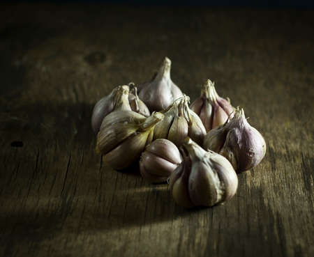 Heads of garlic on old wooden background.