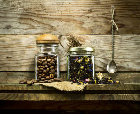 Coffee beans and dry tea in glass jars on the shelf. On a wooden backgroundの写真素材