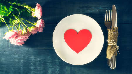 Paper heart in a white plate on a wooden table. Happy Valentine's day background. Festive...