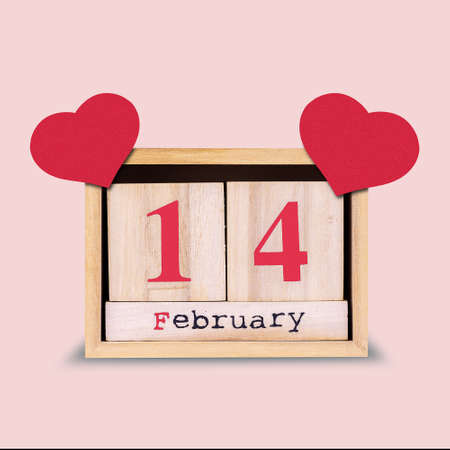14th of February. Wooden calendar with red hearts on a pink background. Valentine's day background....