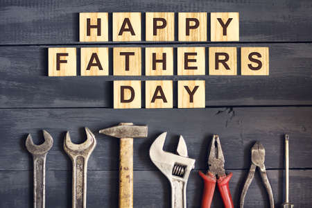 Happy Father's Day inscription on wooden cubes with different paint brushes on a wooden background....