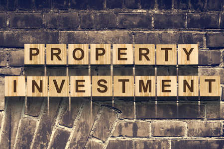 Words, Property Investment, consisting of letters on wooden construction cubes against the background of an old vintage brick wall. Concept business, finance.の写真素材