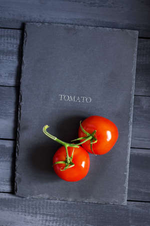 Ripe tomatoes on a stone cutting board. Copy space. Natural, organic products. Dark wooden background.の写真素材