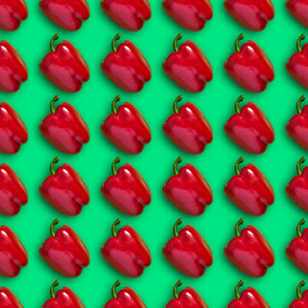 Colorful seamless pattern of red bell peppers on a green background. Concept of creative food. Top Viewの写真素材