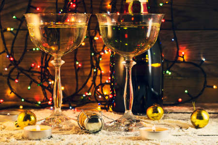 New Year composition with glasses of champagne and with lights on a wooden backgroundの写真素材