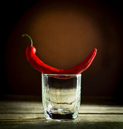 Red hot pepper on a glass of vodkaの写真素材