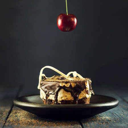 Chocolate cake decorated with cherries on a wooden dark blue backgroundの写真素材