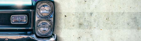The headlight of an old beautiful car on the concrete wall background. Close-up. Copy space. The concept of repair and sale car. Transportの写真素材