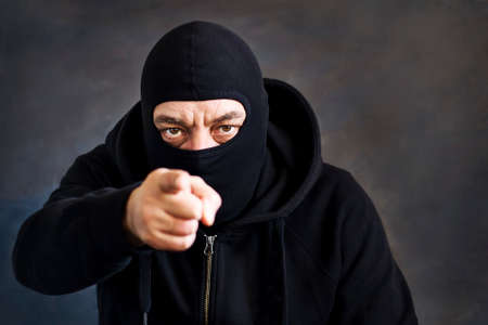 A man in a balaclava on a dark background. Copy space. Concept stealing, deception, kidnapping