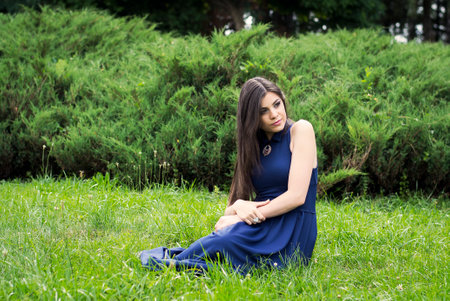 Portrait of a young beautiful girl in a blue dress at the parkの写真素材