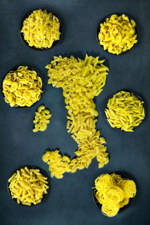 Different types of dry pasta in the form of a map of Italy on a dark blue background