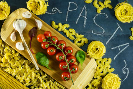 Different types of dried Italian pasta on a blue background. Top view, with chalk written, pastaの写真素材
