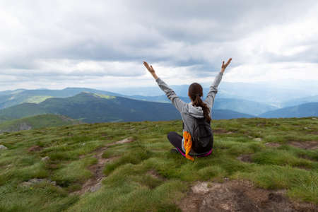 Happy woman with raised hands on the background of beautiful mountains. Success. Travels.