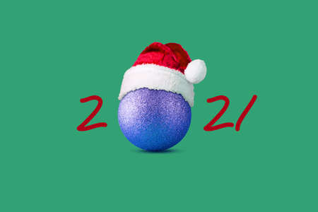 2021, ball in a Santa hat, on a green background. Christmas background. Festive background.